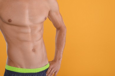 Photo of Shirtless man with slim body on yellow background, closeup. Space for text