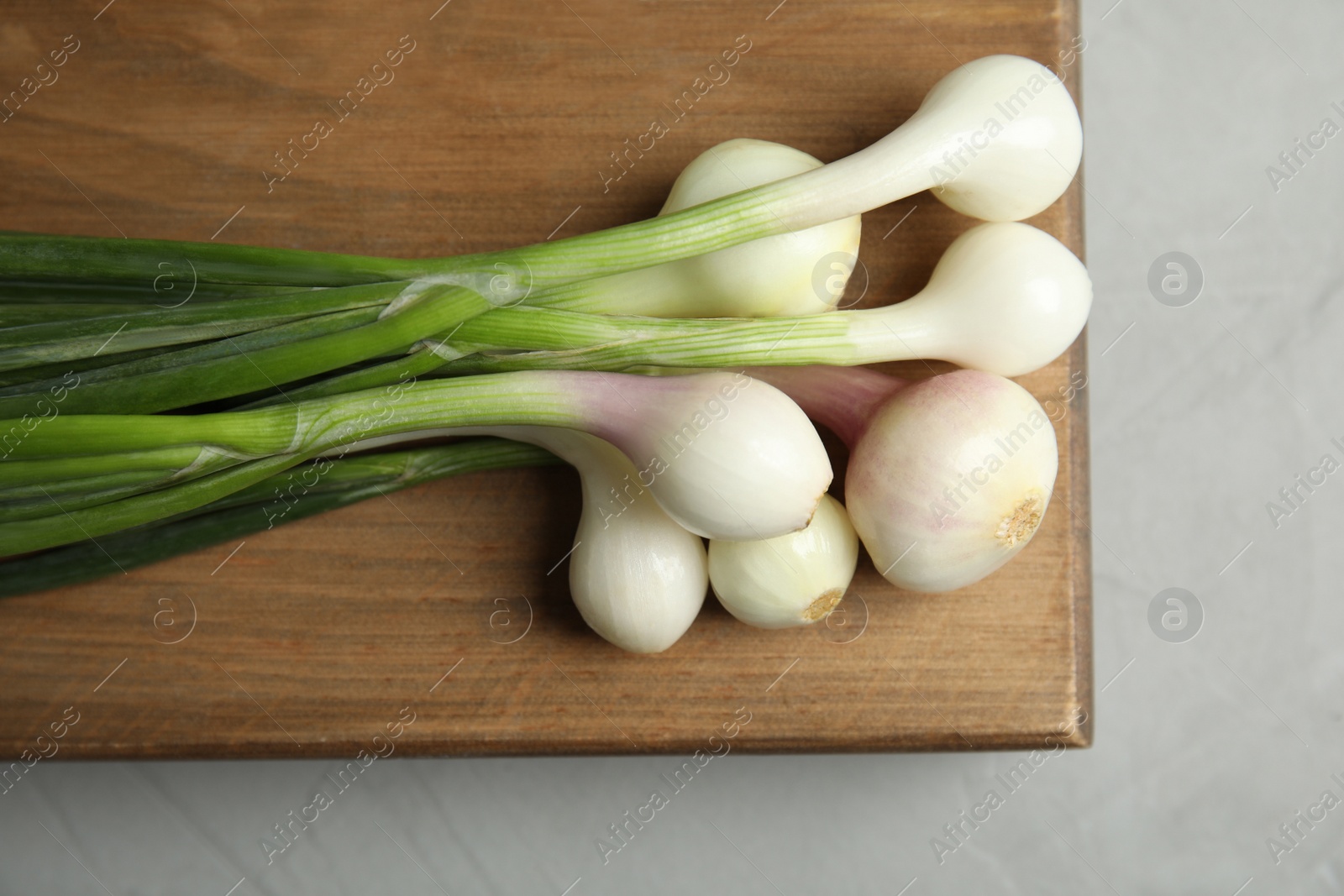 Photo of Fresh green onion on wooden board, top view