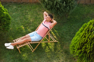 Happy man resting in deck chair outdoors, above view