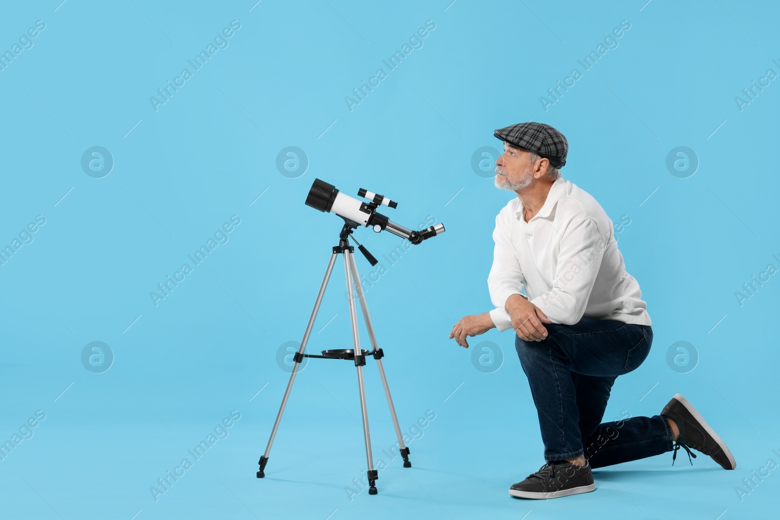 Photo of Senior astronomer with telescope on light blue background
