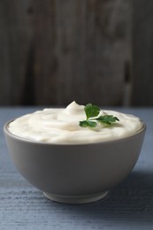 Photo of Tasty mayonnaise and parsley in bowl on gray wooden table, closeup. Space for text