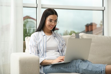 Photo of Young woman with laptop on sofa at home