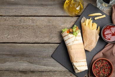 Delicious chicken shawarma and French fries served on wooden table, flat lay. Space for text