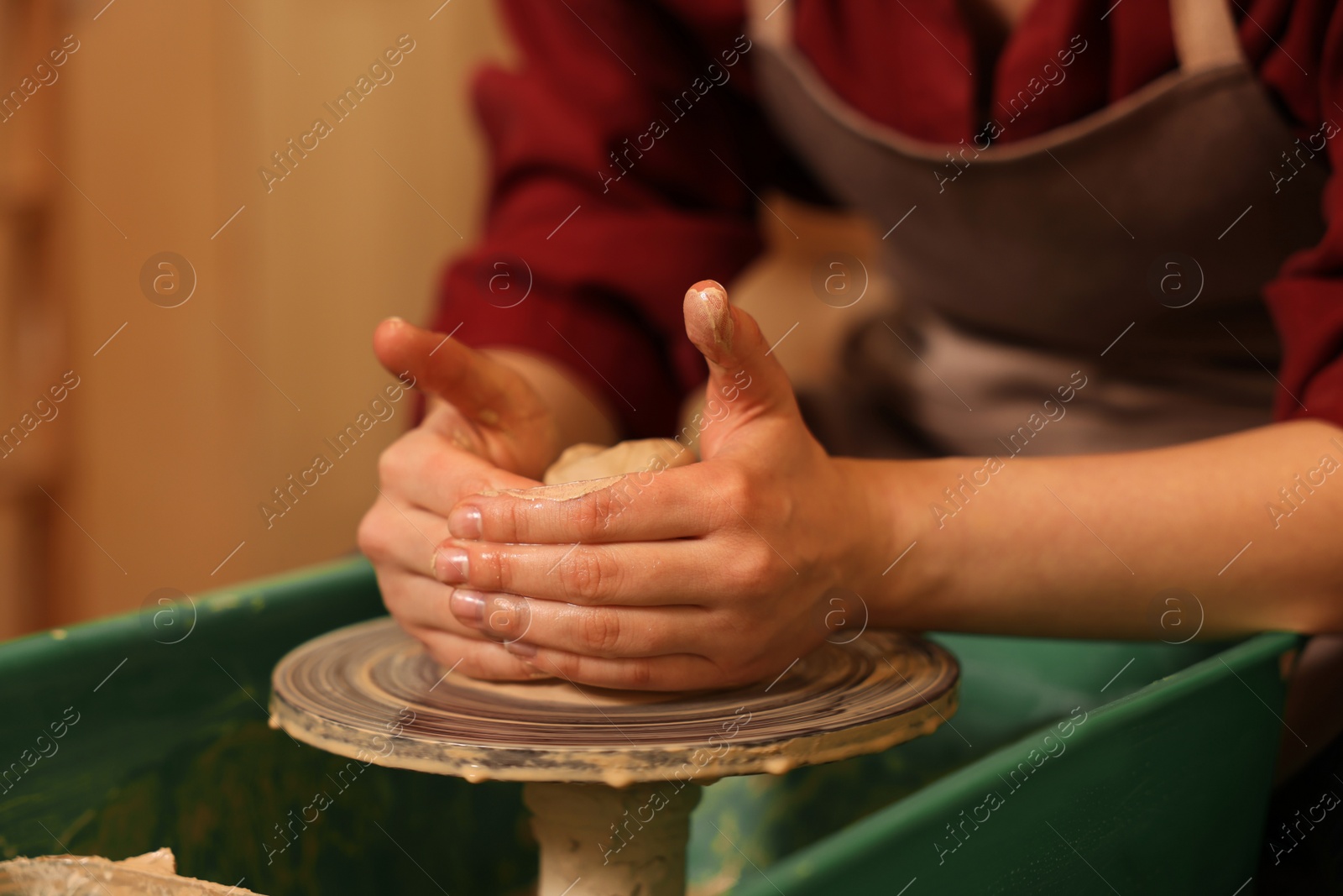 Photo of Woman crafting with clay on potter's wheel indoors, closeup