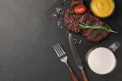 Mug with beer, delicious fried steak and sauce on black table, flat lay