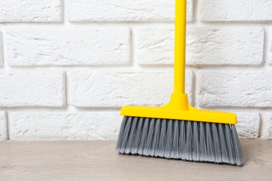 Photo of Plastic broom near white brick wall indoors. Space for text