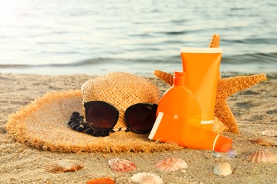 Sun protection products and beach accessories on sand near sea