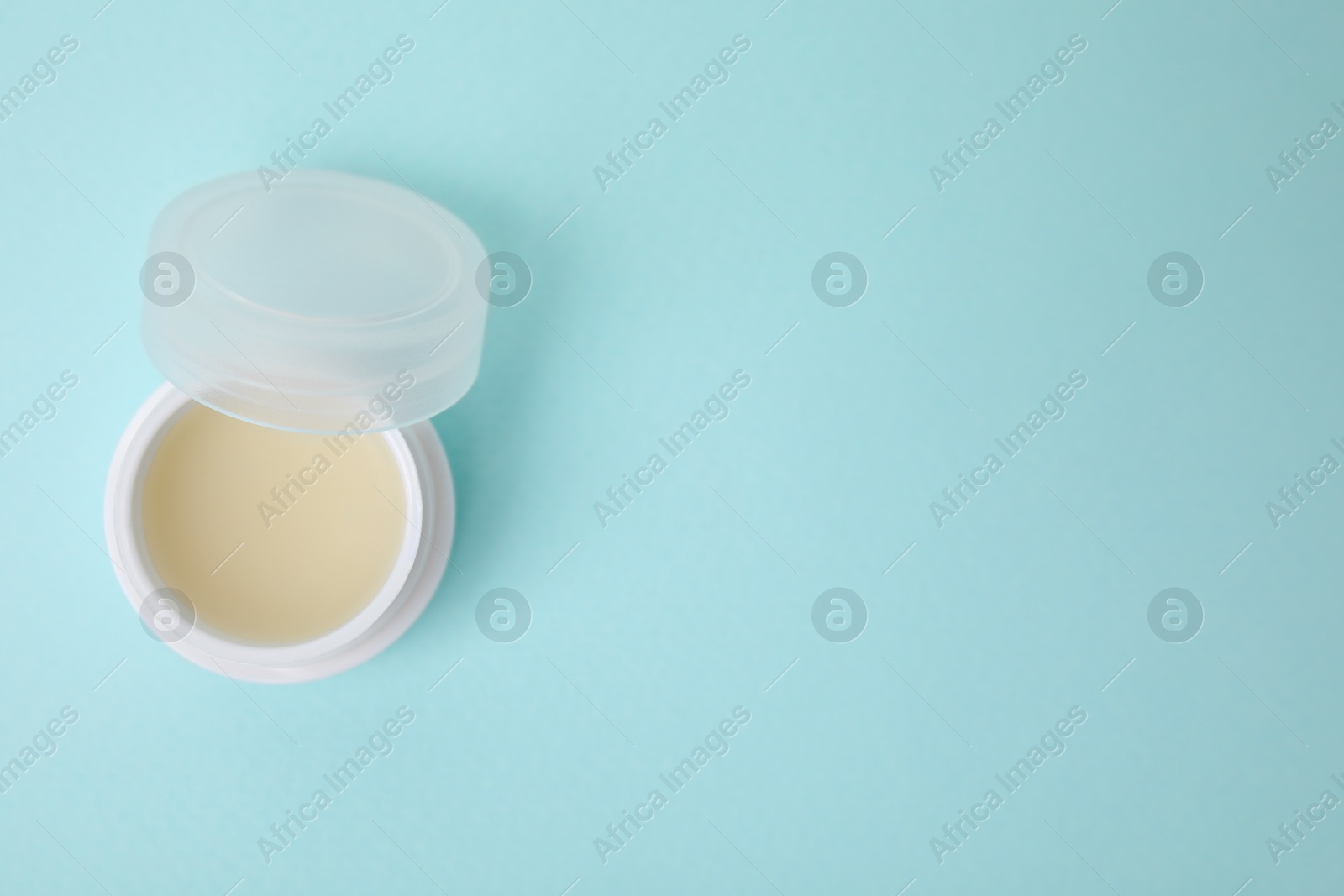 Photo of Jar of petroleum jelly on light blue background, top view. Space for text