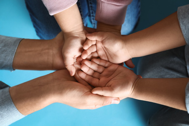 Photo of Happy family holding hands on blue background, top view