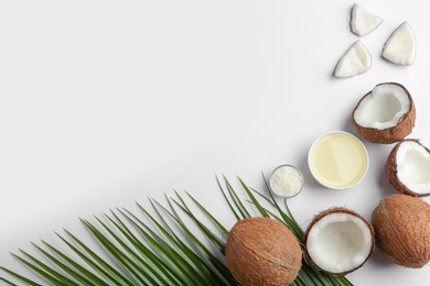 Photo of Bowl of natural organic oil and coconuts on white background, top view. Space for text