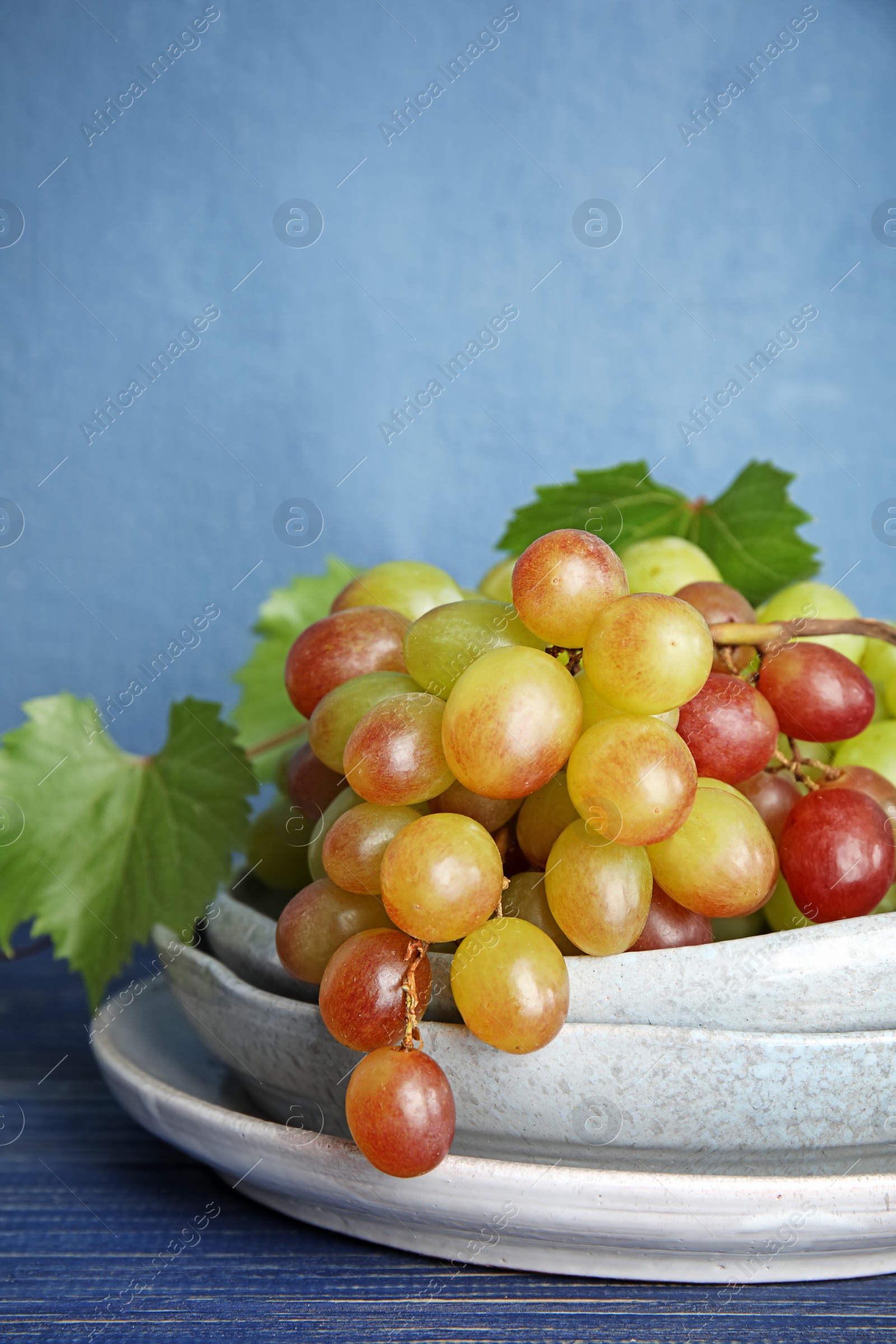 Photo of Fresh ripe juicy grapes in dishware on table