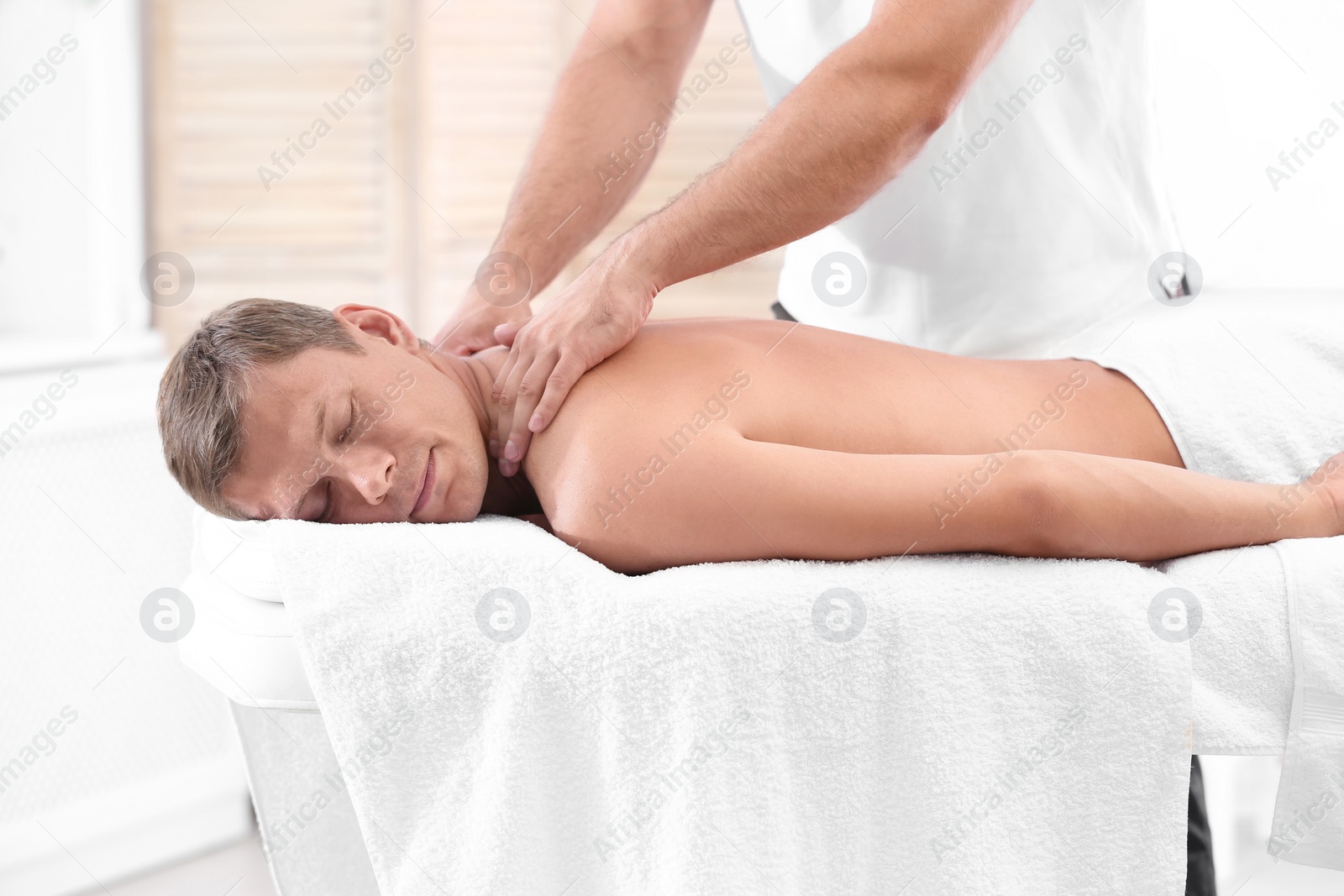 Photo of Relaxed man receiving back massage in wellness center