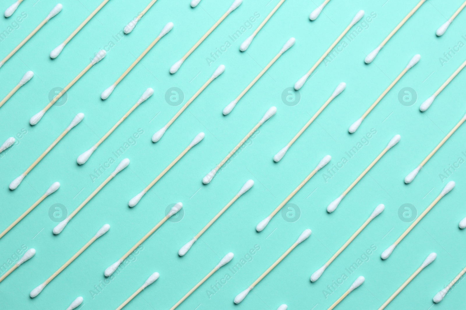 Photo of Many cotton buds on turquoise background, flat lay