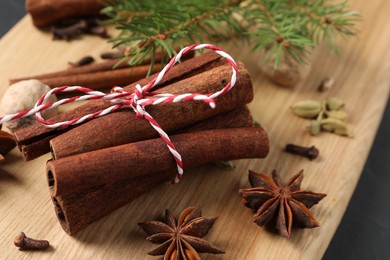 Photo of Cinnamon sticks and other spices on wooden board, closeup