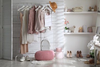 Photo of Rack with different stylish clothes, shoes and decorative elements in dressing room. Interior design