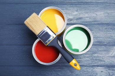 Photo of Flat lay composition with paint cans and brush on wooden background