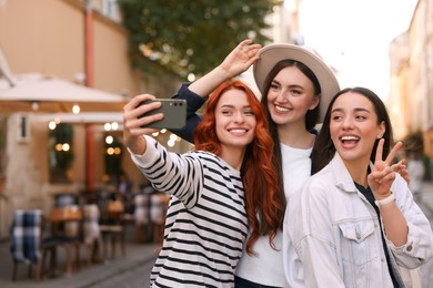 Photo of Happy friends taking selfie on city street