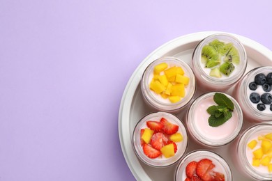 Photo of Yogurt maker with jars and different fruits on lilac background, top view. Space for text