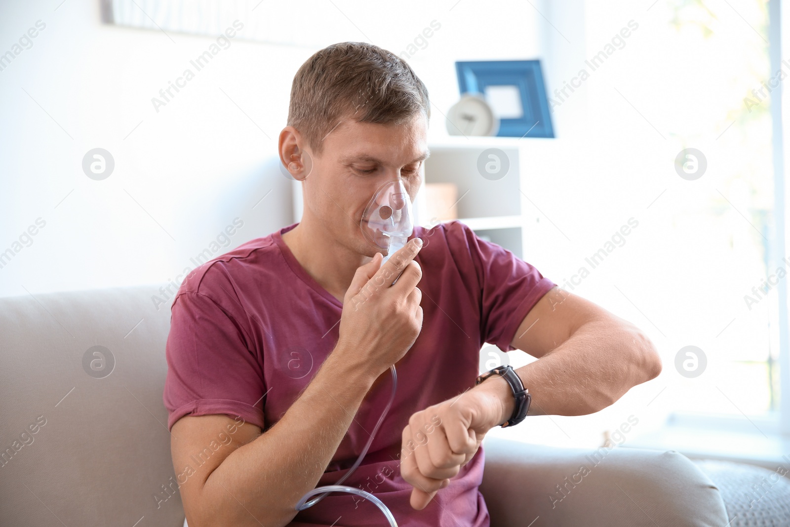Photo of Young man using asthma machine indoors