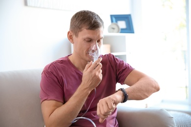 Young man using asthma machine indoors