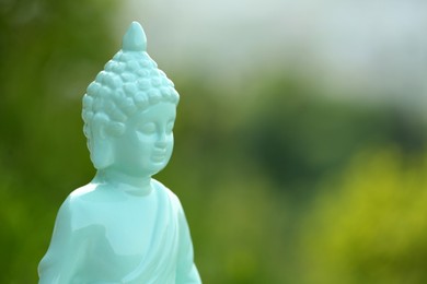 Photo of Decorative Buddha statue on blurred background, closeup. Space for text