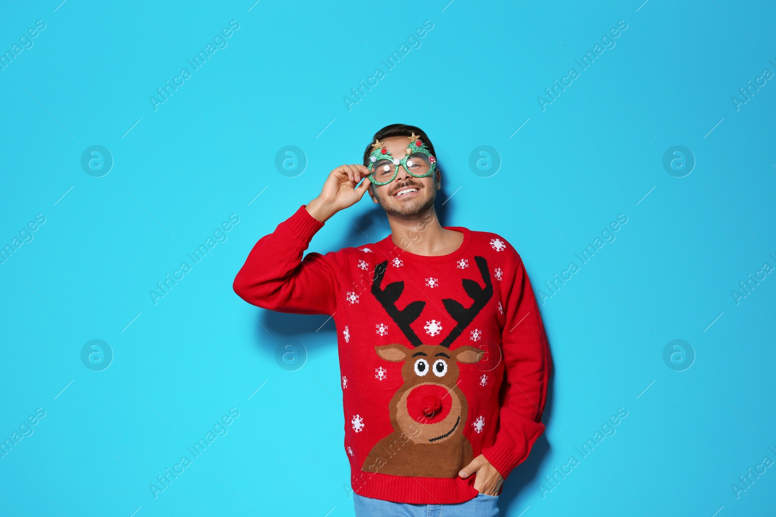 Photo of Young man in Christmas sweater with party glasses on color background