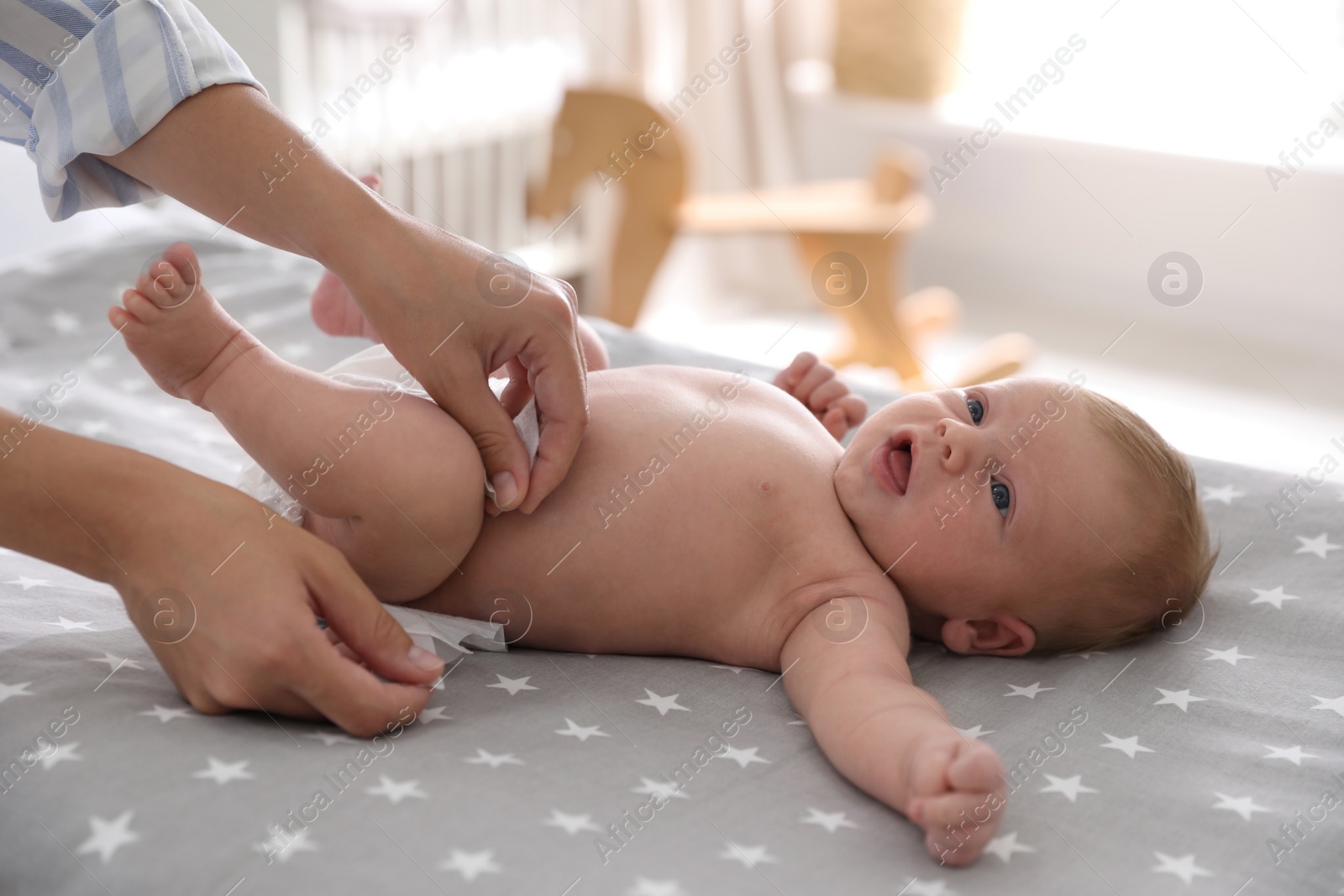 Photo of Mother changing her baby's diaper on bed