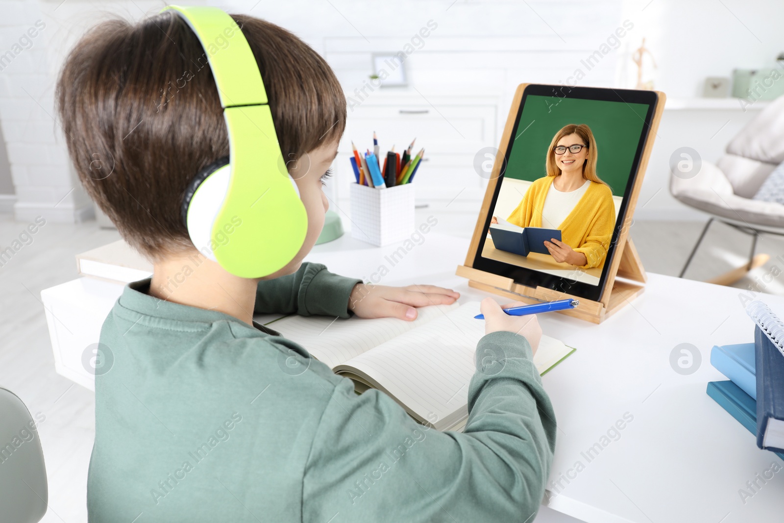 Image of E-learning. Little boy using tablet for studying online at table indoors