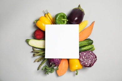 Photo of Flat lay composition with fresh vegetables and blank card for text on gray background