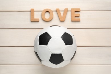Photo of Soccer ball and word Love on white wooden background, flat lay