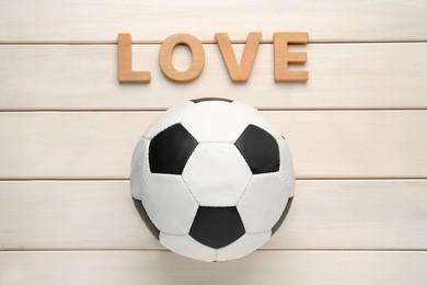 Soccer ball and word Love on white wooden background, flat lay