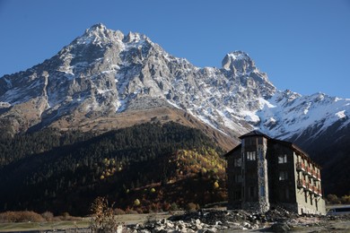 Photo of Picturesque view of high mountains and stone building on sunny day