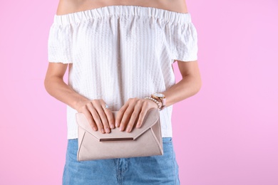 Photo of Young woman in stylish outfit with purse on color background, closeup