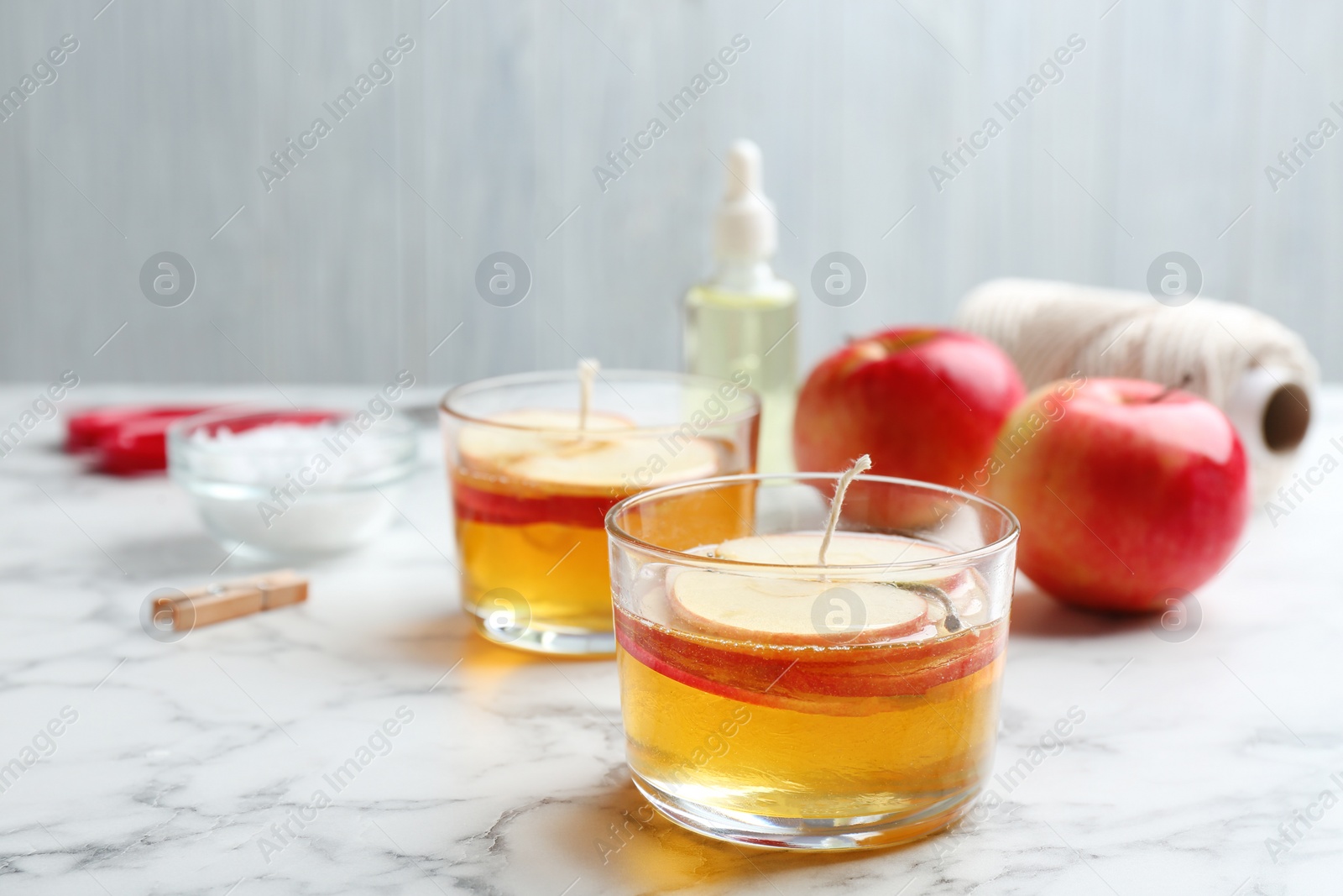 Photo of Handmade apple candles and ingredients on marble table