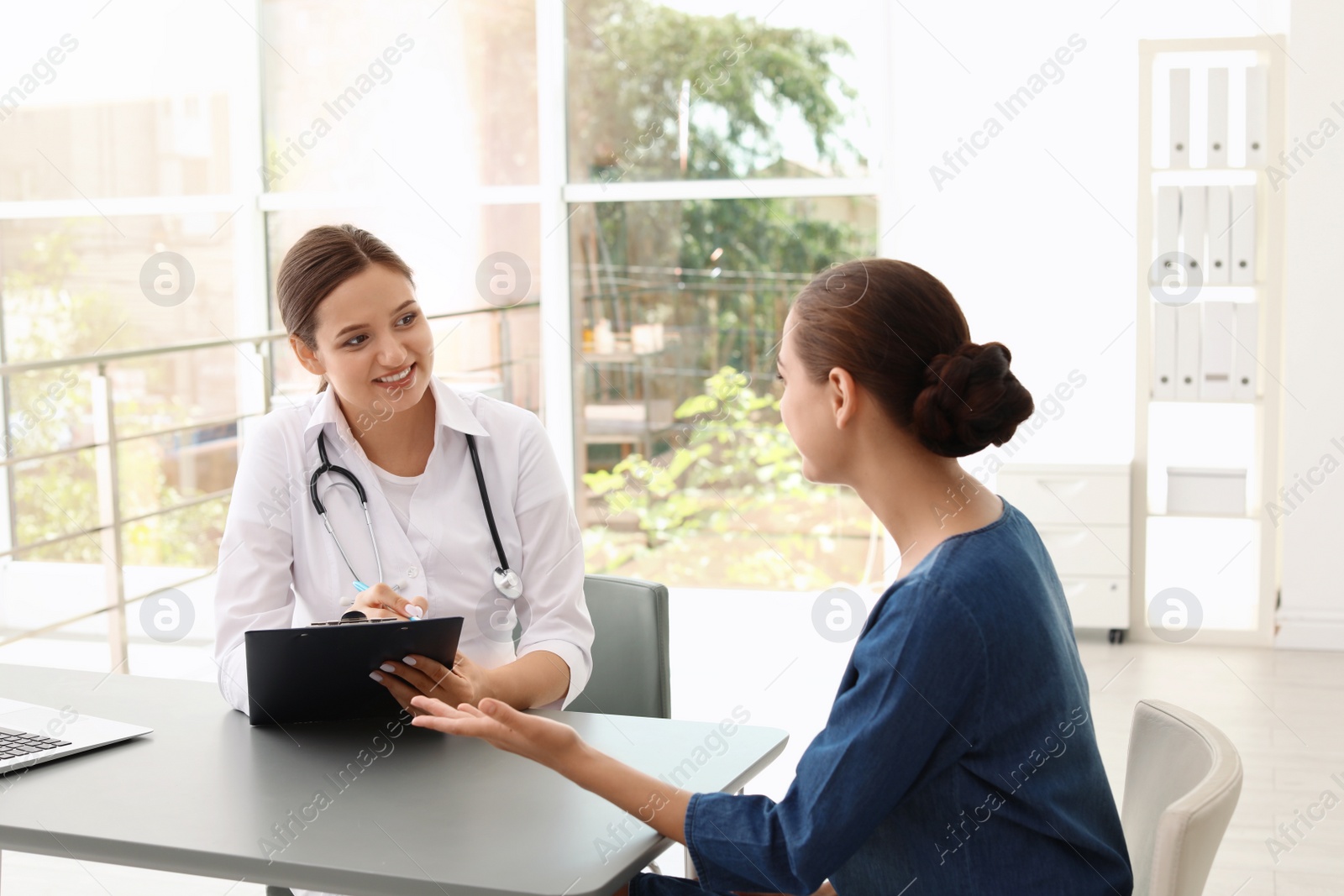 Photo of Young doctor listening to patient's complaints in hospital