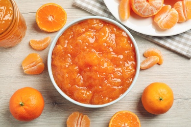 Flat lay composition with delicious tangerine jam on wooden table