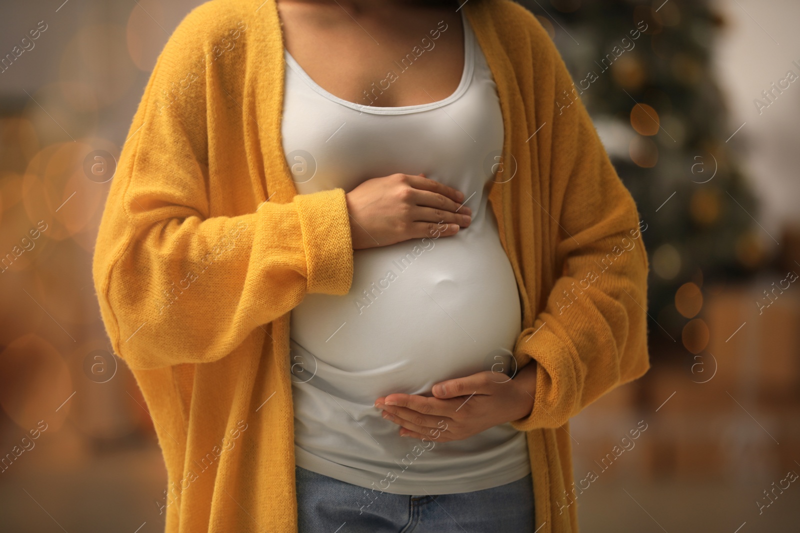 Photo of Pregnant woman in room decorated for Christmas, closeup. Expecting baby