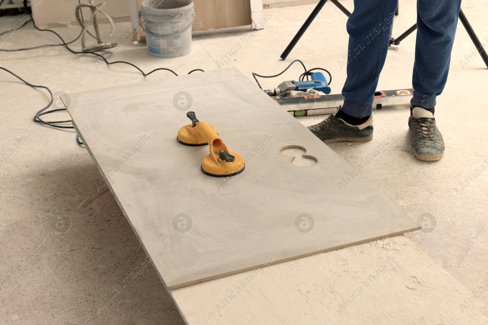 Photo of Worker near tile with glass suction plate indoors, closeup