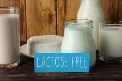 Photo of Card with phrase Lactose free and different fresh products on wooden table