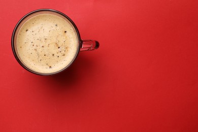 Photo of Fresh coffee in cup on red background, top view. Space for text