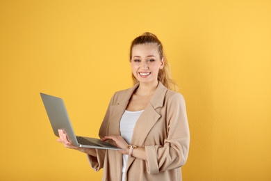 Photo of Portrait of beautiful young woman with laptop on yellow background