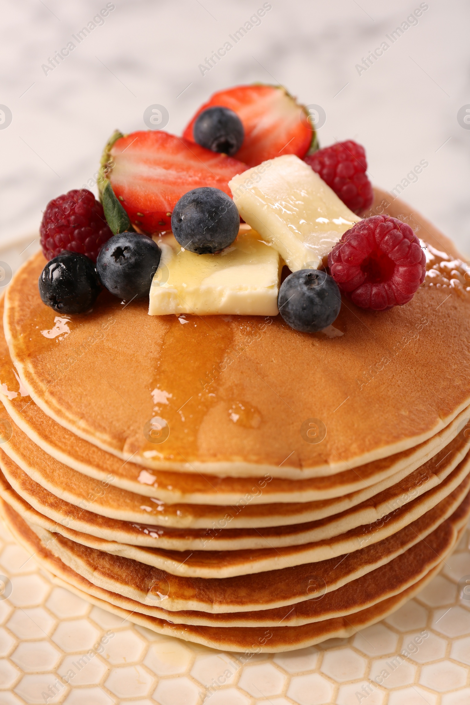 Photo of Delicious pancakes with fresh berries, butter and honey on plate, closeup