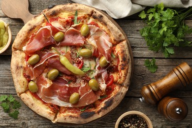 Tasty pizza and ingredients on wooden table, top view