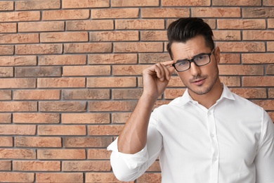 Photo of Portrait of handsome young man and space for text on brick wall background