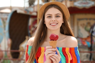 Young happy woman with ice cream cone in amusement park