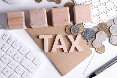 Word Tax, wooden cubes, calculator, coins, keyboard and pen on white table