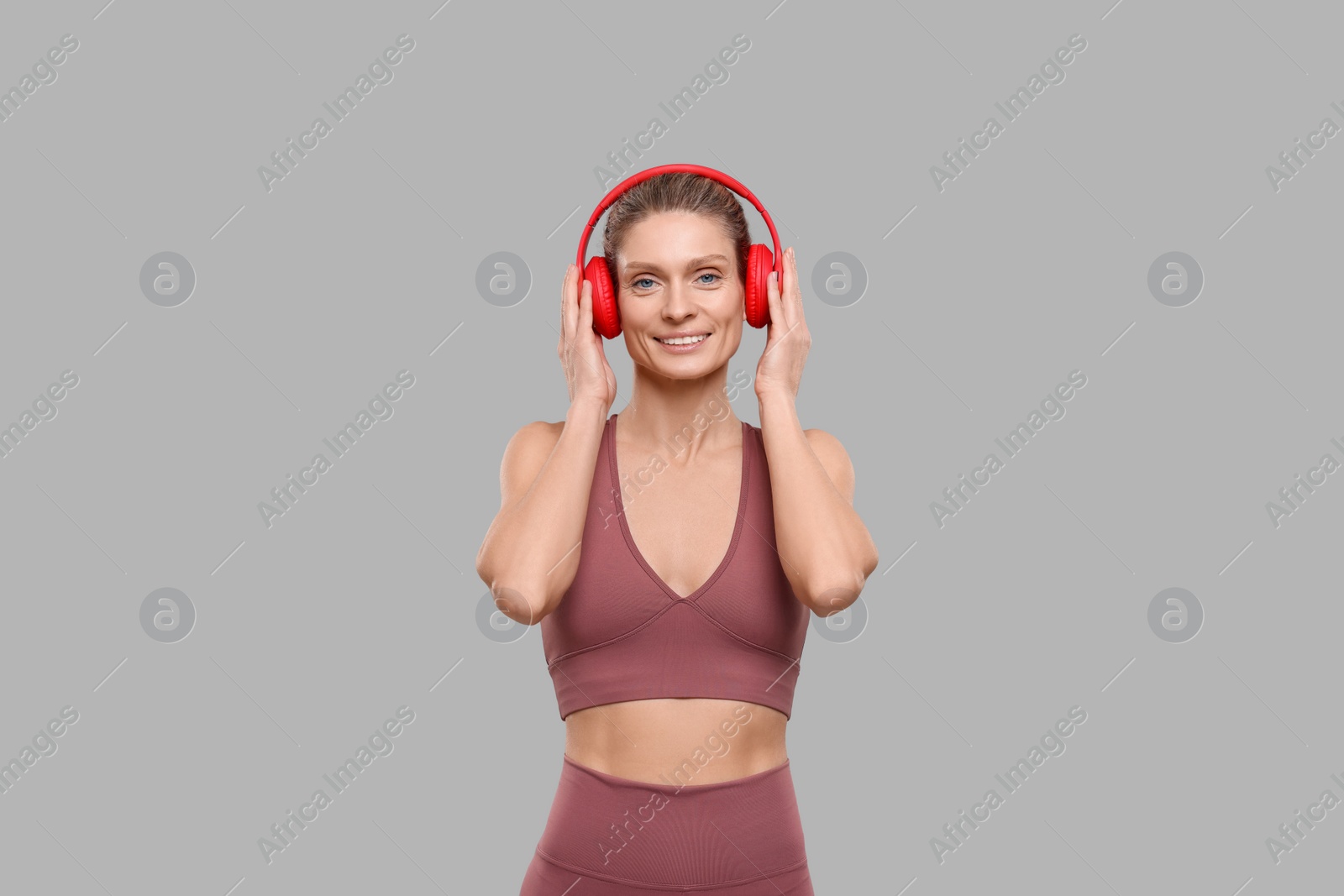 Photo of Portrait of sportswoman with headphones on grey background