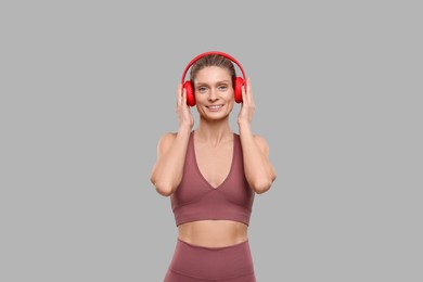 Portrait of sportswoman with headphones on grey background