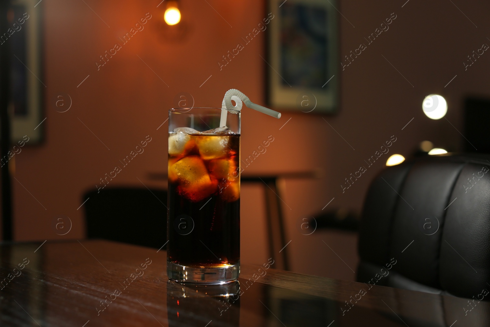 Photo of Glass of cold cola on table in dark room. Space for text