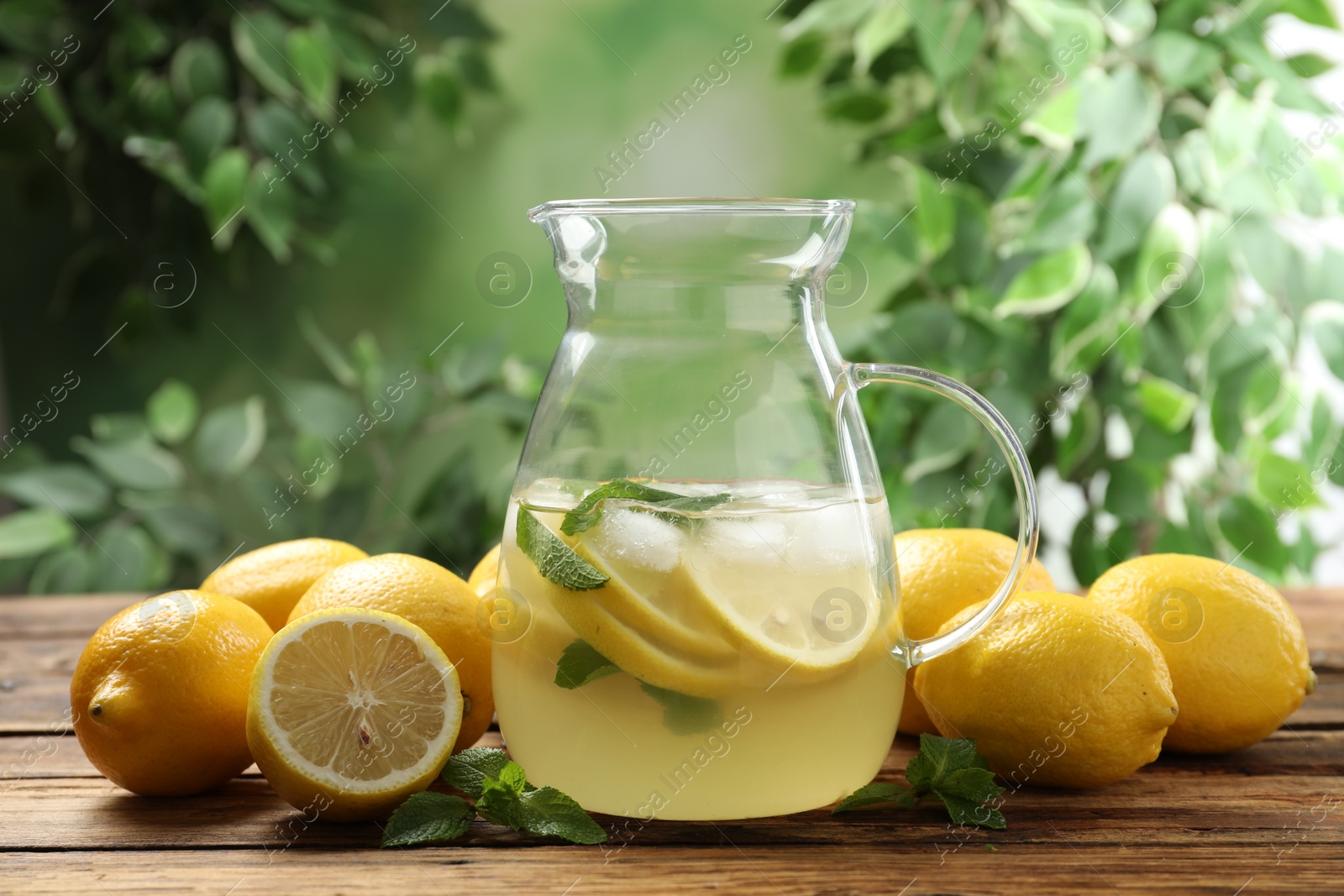 Photo of Natural lemonade with mint and fresh fruits on wooden table against blurred background. Summer refreshing drink